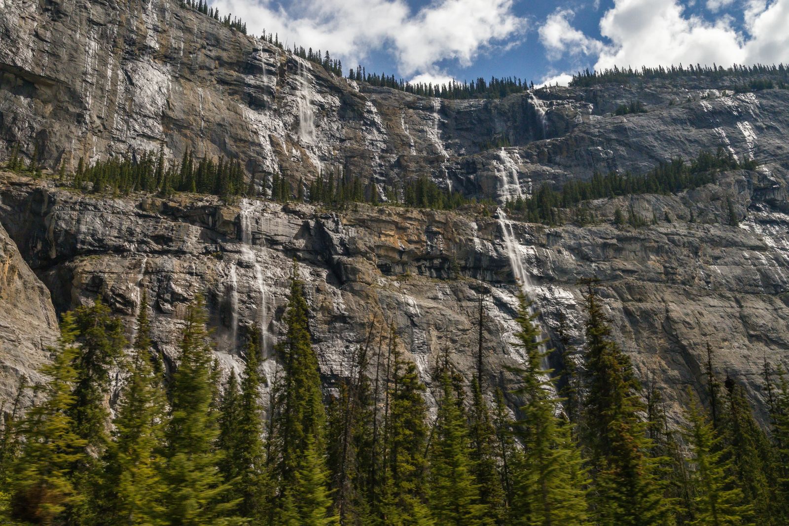 multiple waterfalls cascading down a limestone cliff that makes it appear that the mountain is weaping