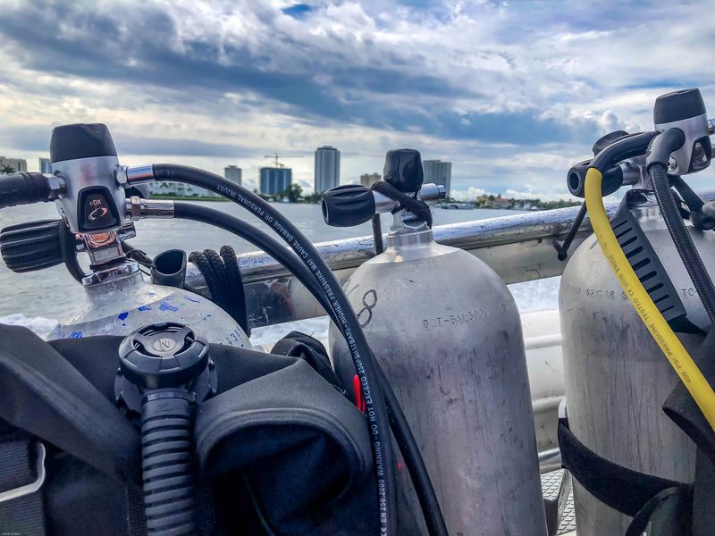 Diving Singer Island Florida - Scuba tanks on a boat rail with singer island hotels in the background