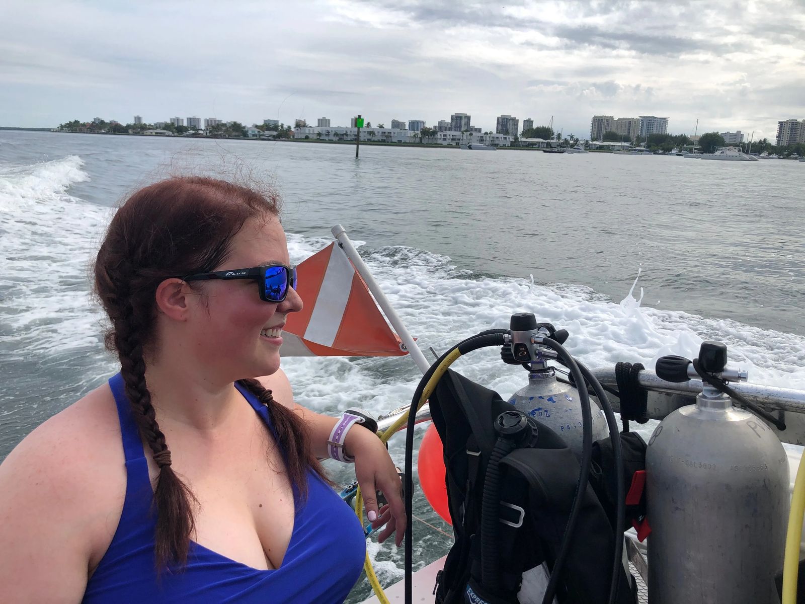 Janiel with city in the background with dive flag and scuba tanks