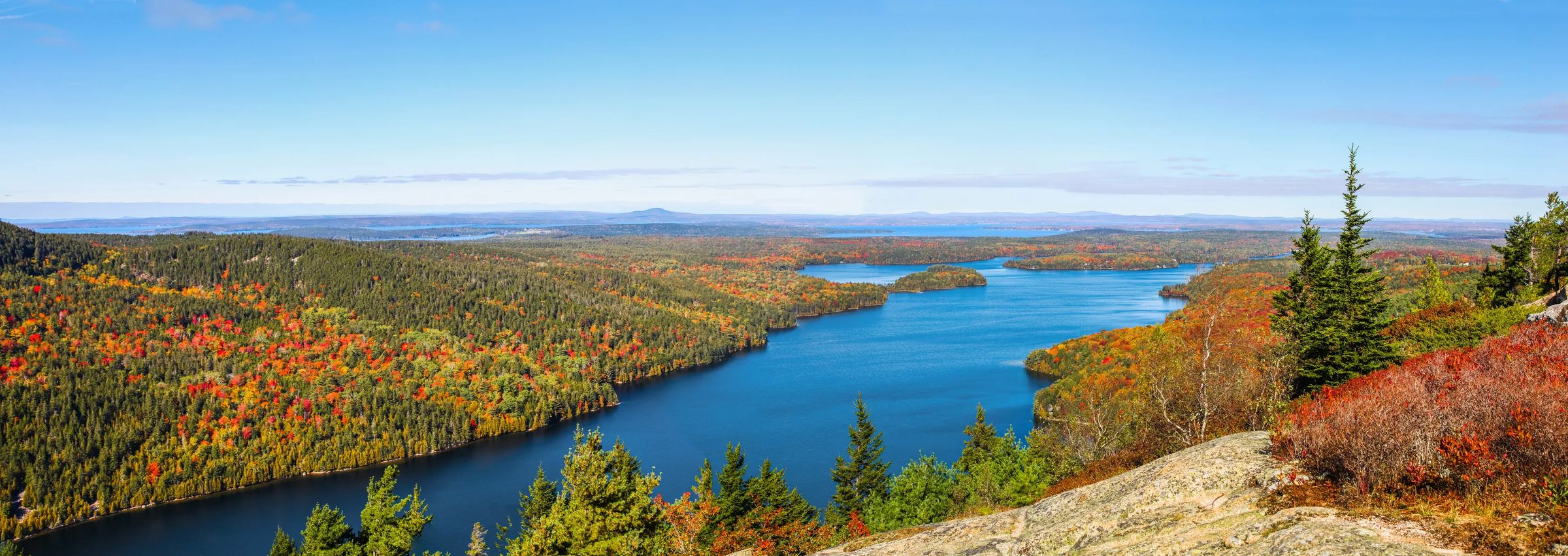 view from a mountain peak in acadia national park with beautiful orange and green fall colors