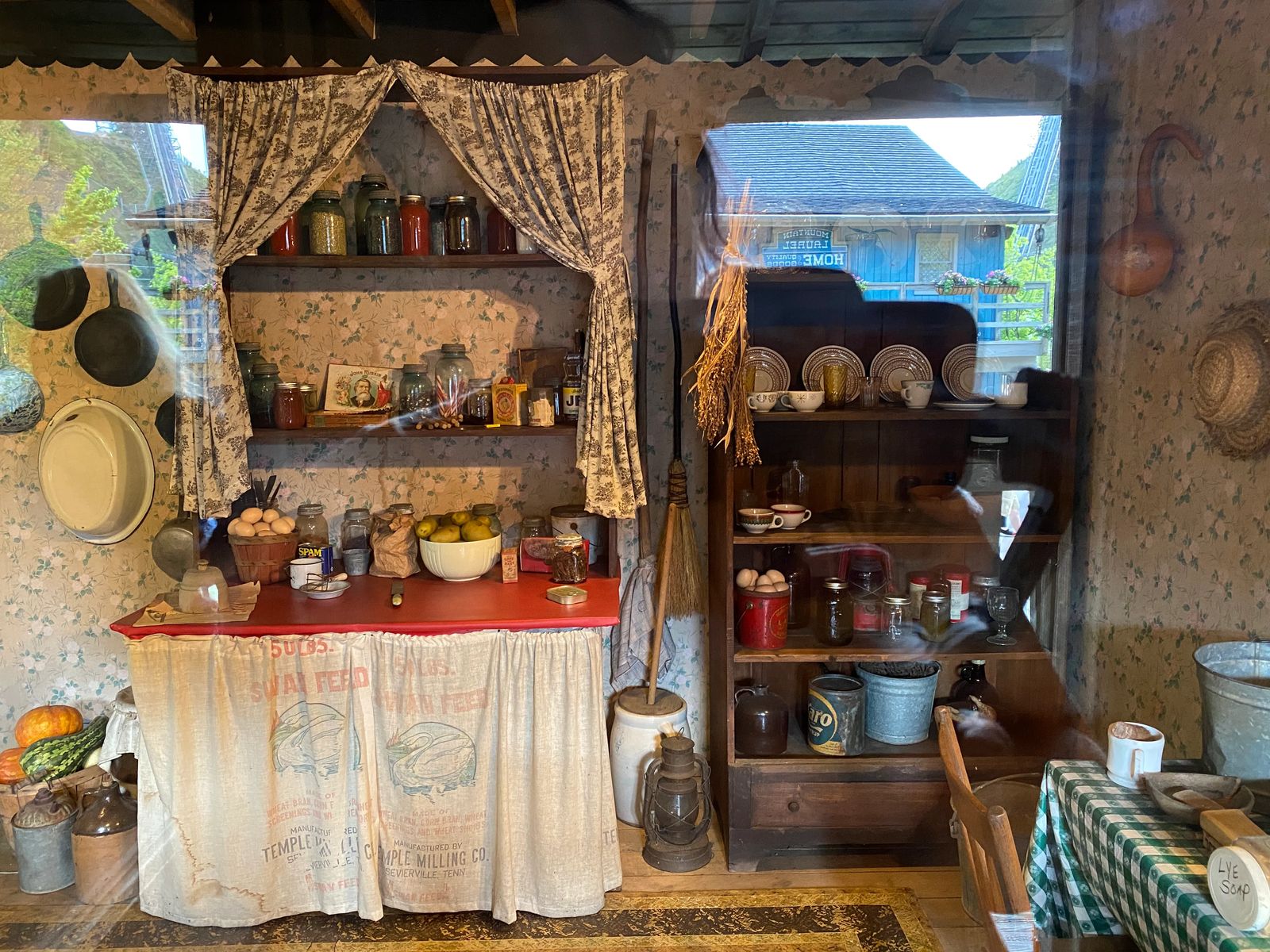 wooden shelf with canned items and curtains for cupboards and butter churner in the corner, guide to dollywood