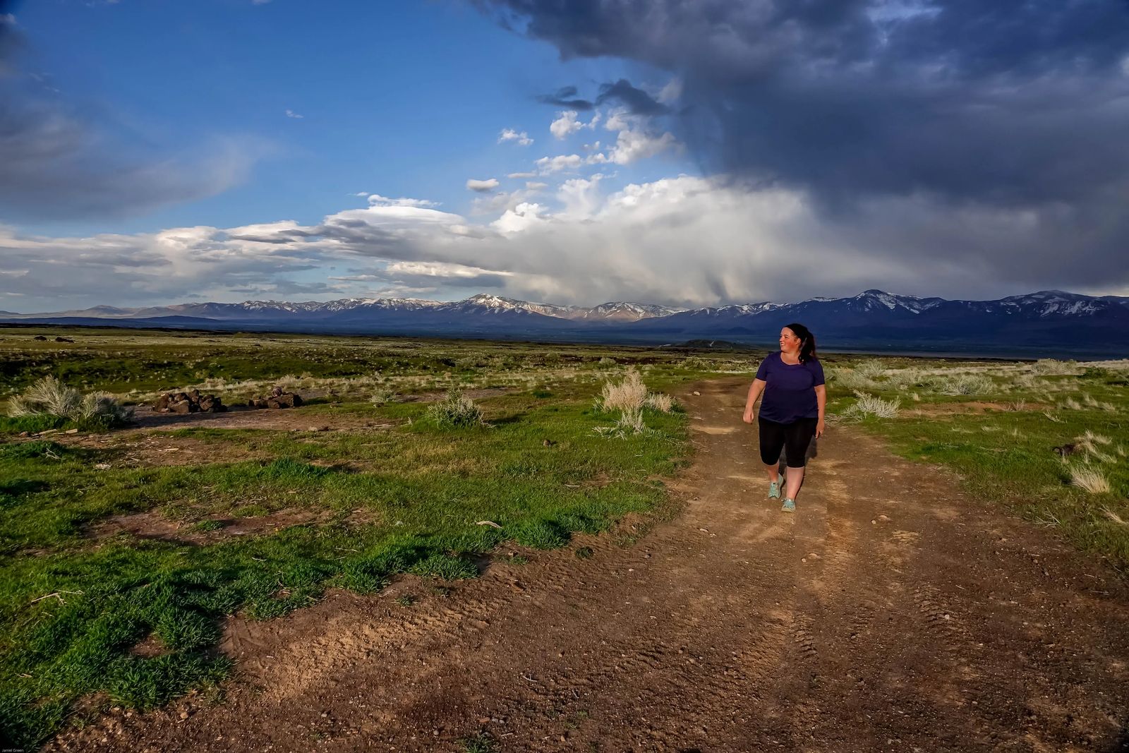 walking in feild with mountains behind woman