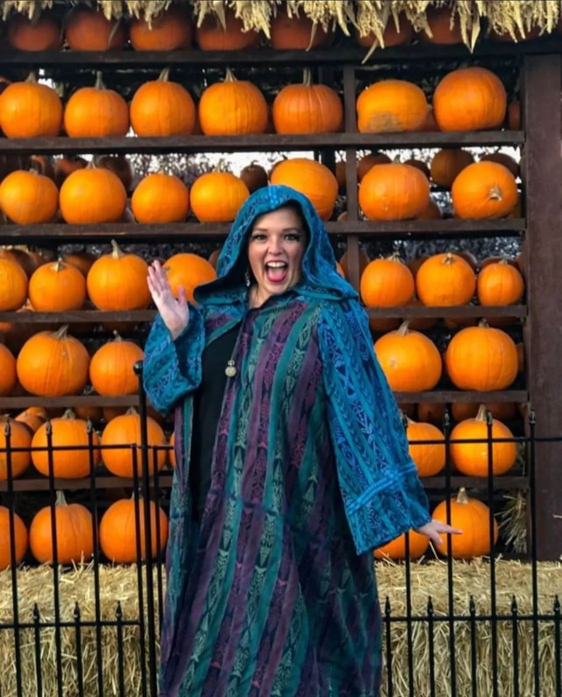 Janiel in front of pumpkin wall dressed in mystical robes