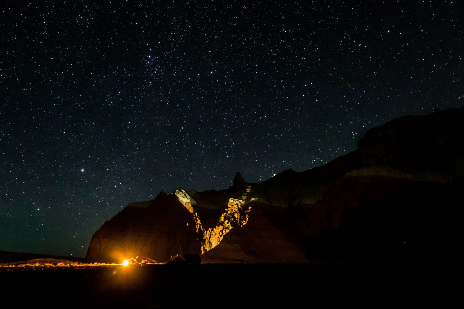 Night sky in Goblin Valley with camping fire lighting the mountain