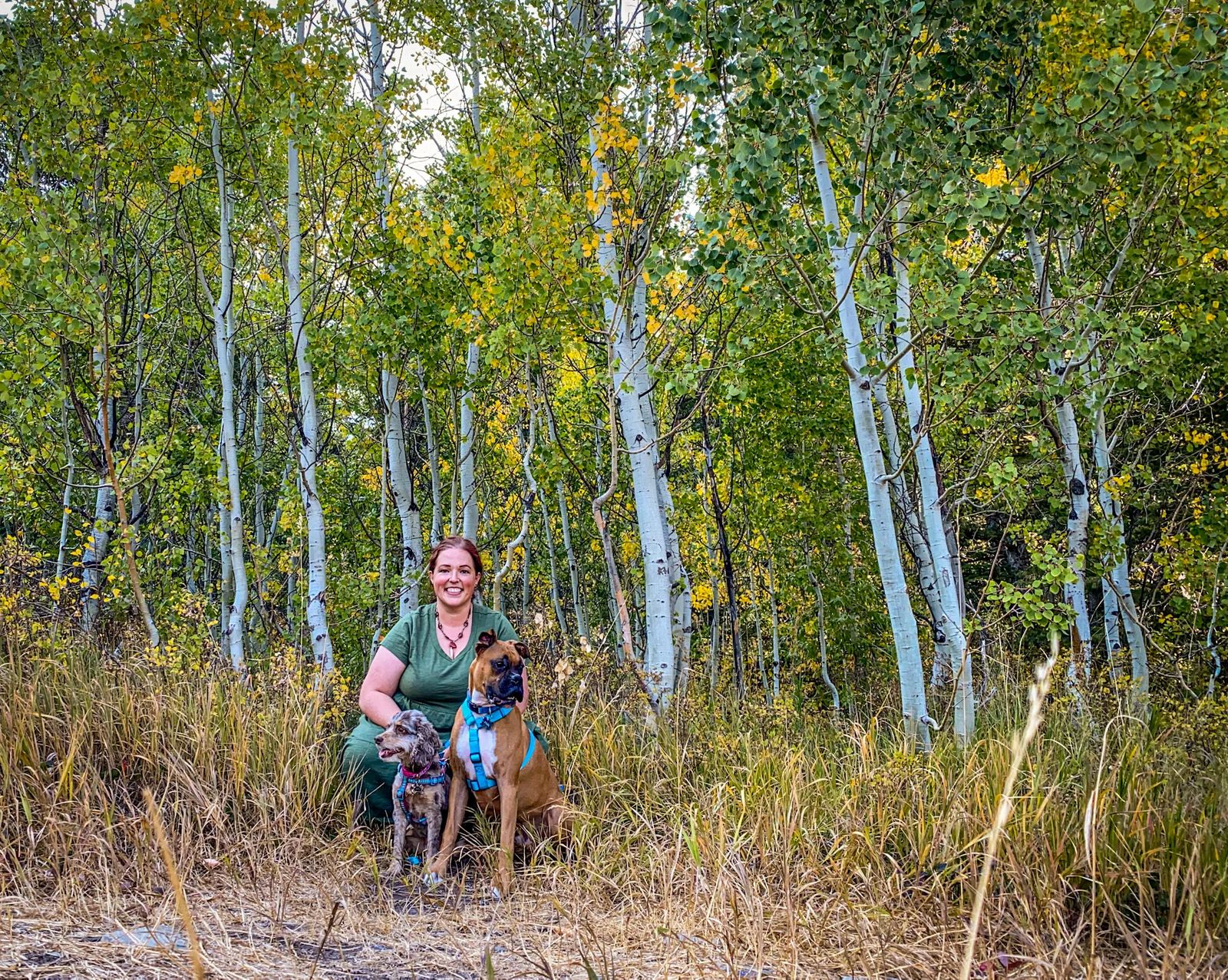 Janiel with her dogs in front of aspen trees starting to turn yellow