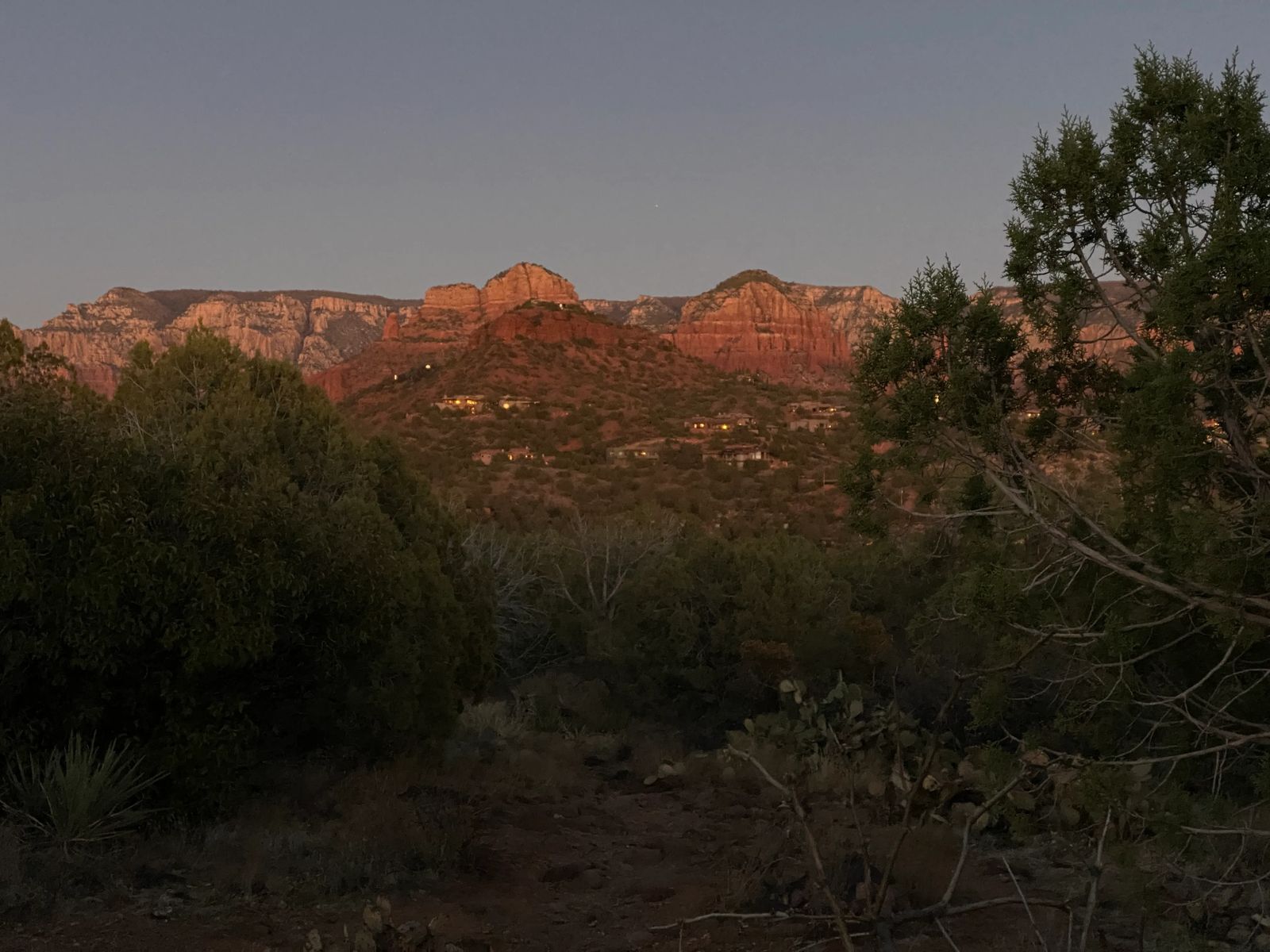 Lights in houses turning on with red rocks behind them