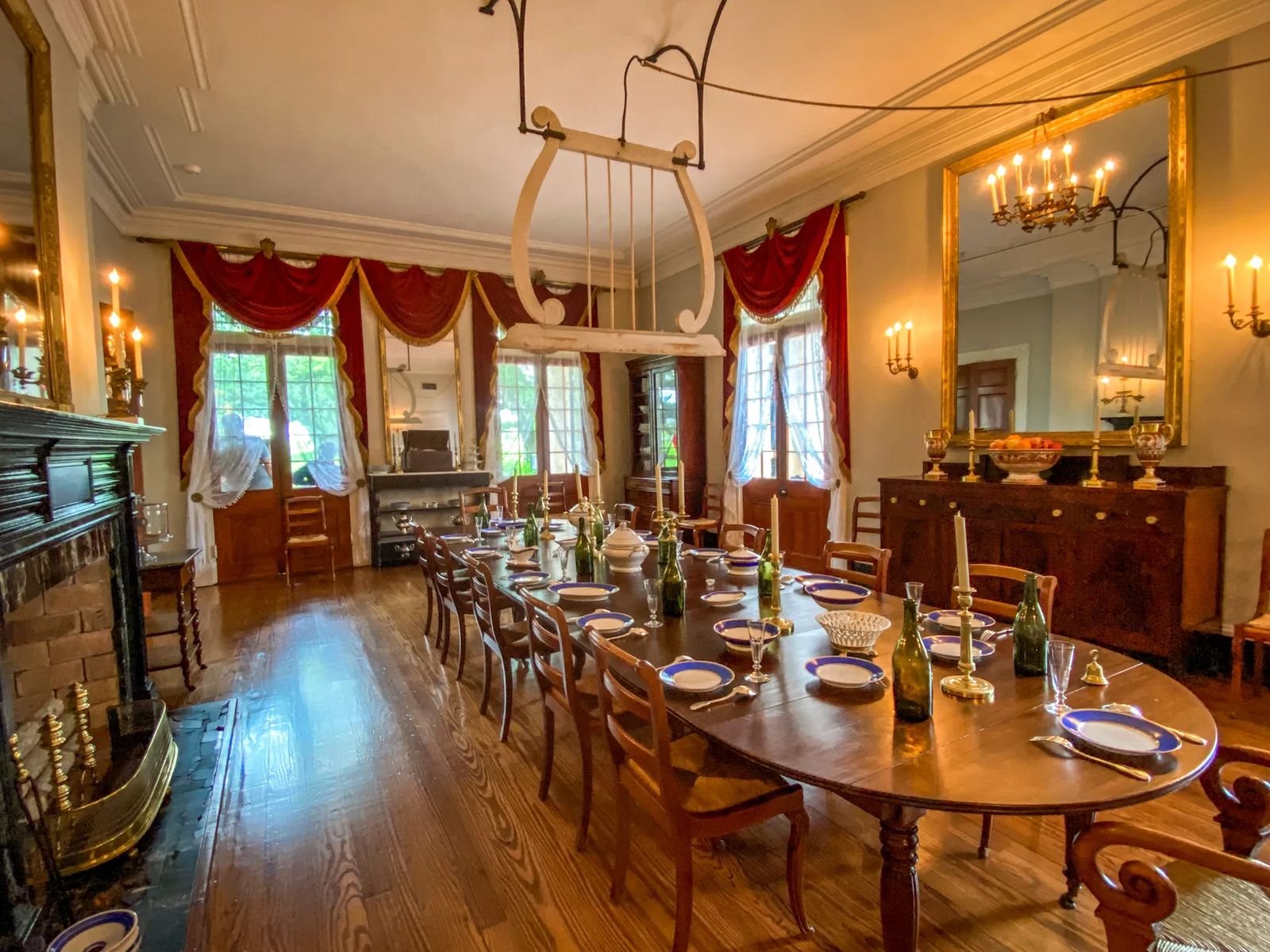 18th century table with wine bottles blue and white tableware and large wooden fan connected to rope