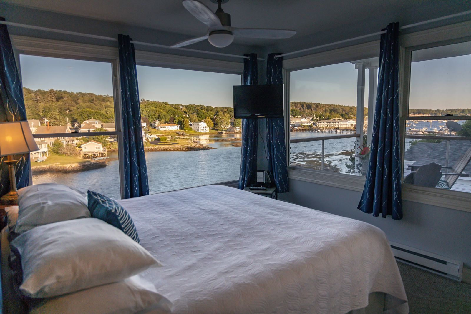 two walls of windows in a cozy bright hotel room overlooking Boothbay at sunset